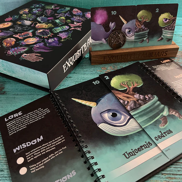 A large deck box with various creatures on it, a wooden card holder showing two oracle cards, and then a spiral booklet in the foreground showing a guide with lore and wisdom