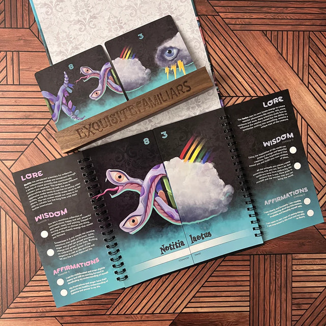 A wooden card holder with two oracle cards and an open double-spiral bound notebook showing lore and wisdom.