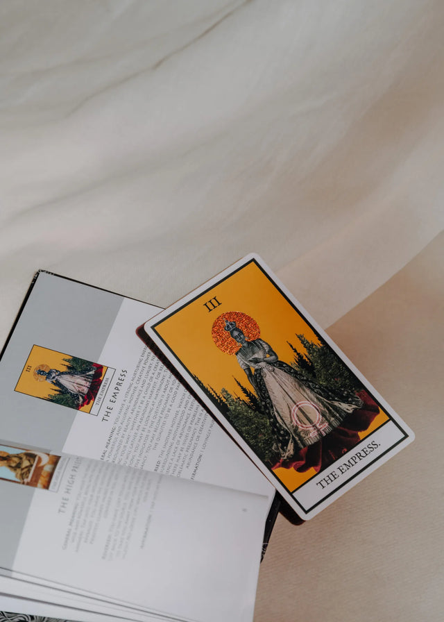 A tarot card, The Empress, from the Tazama African Tarot deck laying on the guidebook