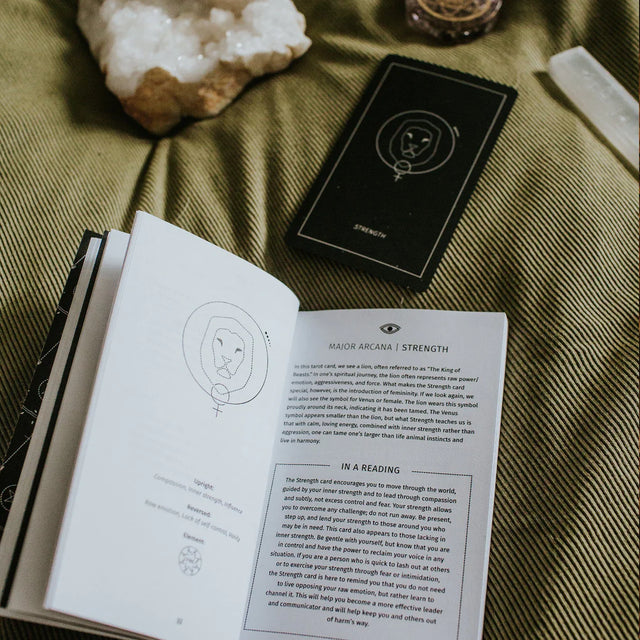 The Synesthesia Tarot Guidebook open to the page describing the card Strength, with the card behind it and a crystal