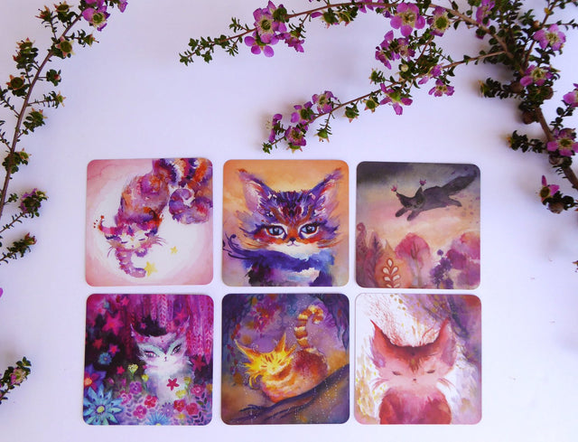 A selection of pink/red/purple cards from the Spirit Cats Oracle Deck with pink flowers around them.
